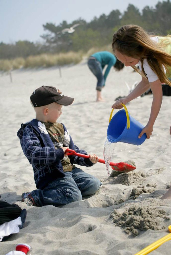 Kinder spielen mit Schaufel und Eimer am Ostseestrand.