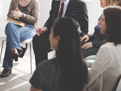 Menschen sitzen in einem Kreis während eines Gesprächsseminars.