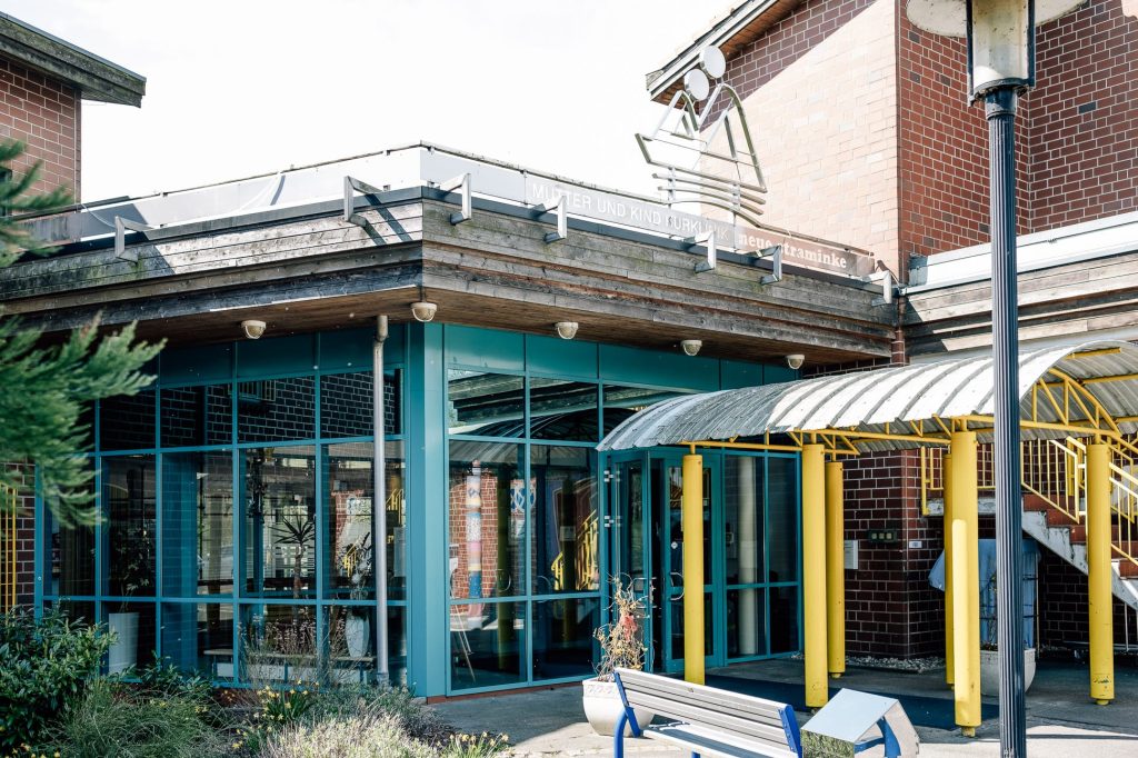 Ostseeklinik Zingst: Moderner Eingang mit verglastem Anbau, Metallskulptur und Aufschrift "Mutter und Kind Kurklinik".