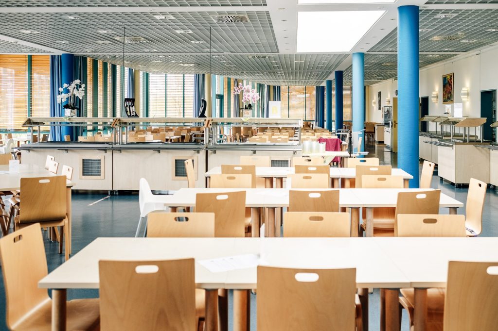 Der helle Speisesaal der Ostseeklinik Zingst mit weißen Tischen und hellen Holzstühlen.